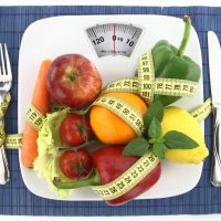 Fruits and vegetables with measuring tape on a plate as weight scale