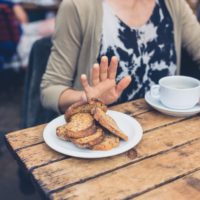 Young woman on gluten free diet is saying no thanks to toast in a cafe