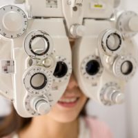 Female patient looking through phoropter during eye exam