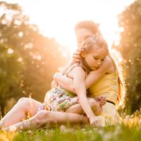 Mother cuddling her worried child outdoor in nature