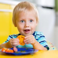 Cute young boy eating fresh vegetables