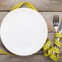 Empty plate with measure tape, knife and fork