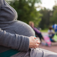 Pregnant woman sitting on park bench