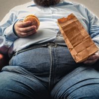 overweight man eating burger