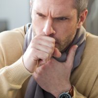 Man with whooping cough feeling sick with a scarf on