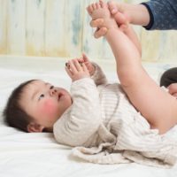 Asian baby with nappy rash having bottom cleaned and nappy changed