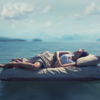 Sleeping woman lies on airbed floating on a lake