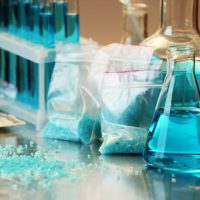 Blue methamphetamine and liquid in flasks on table in laboratory