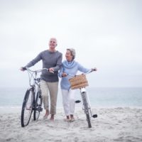 Senior couple having ride with their bike on the beach
