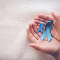 Hands holding sky blue ribbons for prostate cancer awareness