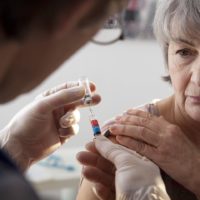 Elderly lady having the shingles vaccine administered by a doctor
