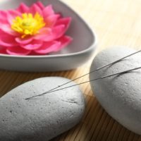 Acupuncture needles with stones on bamboo mat