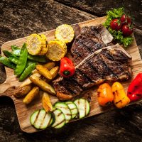 Delicious steakhouse porterhouse steak and colorful fresh roast vegetables, view from above