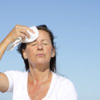 Portrait of a stressed and exhausted looking middle aged woman trying to cool down face because she is going through menopause