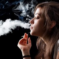 Woman Smoking a Cigarette on Black Background