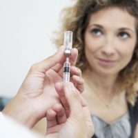 Woman looking at doctor who is about to administer a flu vaccine