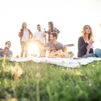 Group of friends relaxing on the grass in the summeritme having a good time together