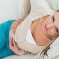 Woman lying on the bed suffering from a bad stomach bug