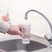 Fluorinated Water Flows into a Glass Held by a Hand