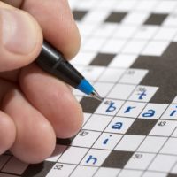 Man is holding a pencil in his hand and there are words 'train' and 'brain' already written in the crossword