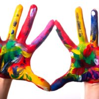 Rainbow coloured hands held up in front of a white background