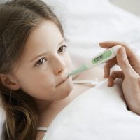 Young Sick Girl with Thermometer in Mouth
