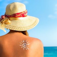 Woman with sunscreen avoiding skin cancer looking out to the ocean