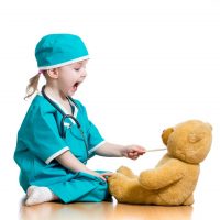 Child pracitcing safely feeding medicine to her teddy bear
