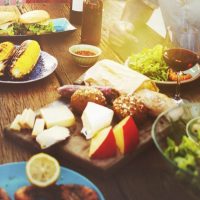 Group eating delicious food around the table in the summer sun