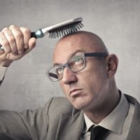 Bald man trying to brush his hair