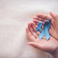 Hands holding sky blue ribbons for prostate cancer awareness