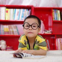 boy with eyeglasses in front of bookshelf