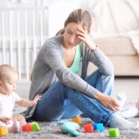 Depressed young woman with cute baby at home