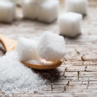 White sugar in wood spoon on wood table