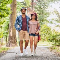 Young couple walking on pathway through grass field