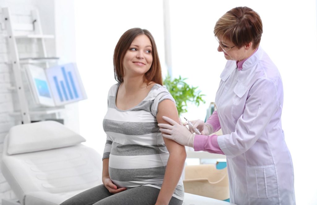 Pregnant lady being given a flu injection by the doctor