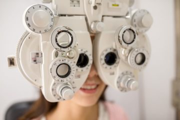 Female patient looking through phoropter during eye exam
