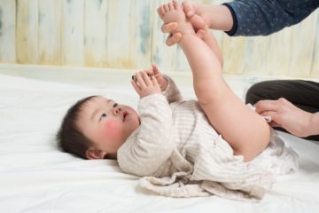 Asian baby with nappy rash having bottom cleaned and nappy changed