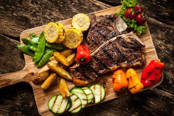 Delicious steakhouse porterhouse steak and colorful fresh roast vegetables, view from above