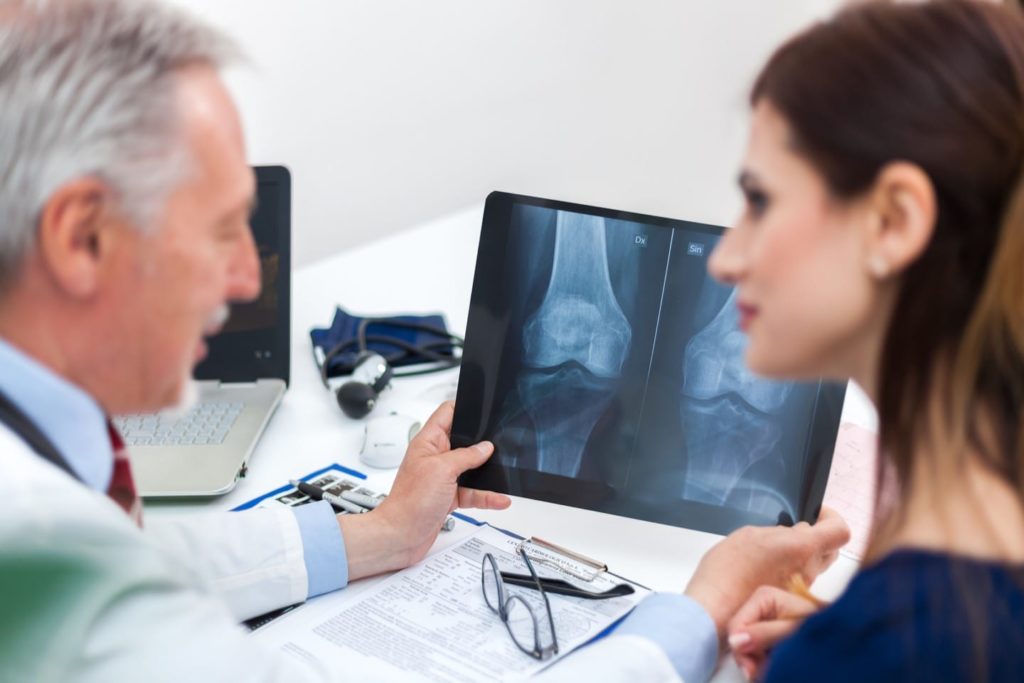 Doctor showing a radiography to his patient and diagnosing osteoporosis