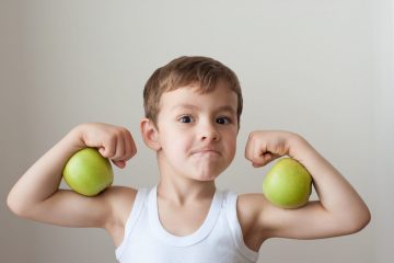 Boy with green apples showing biceps after strength training