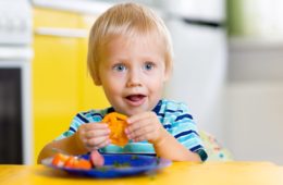 Cute young boy eating fresh vegetables