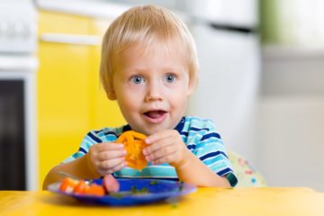 Cute young boy eating fresh vegetables