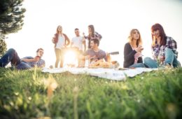 Group of friends relaxing on the grass in the summeritme having a good time together