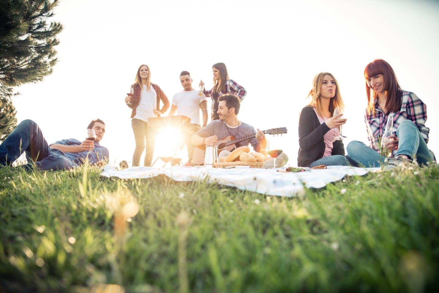 Group of friends relaxing on the grass in the summeritme having a good time together