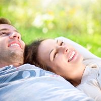 Happy Smiling Couple Relaxing on Green Grass in the Park