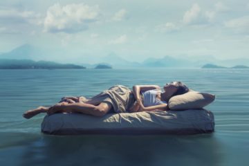 Sleeping woman lies on airbed floating on a lake