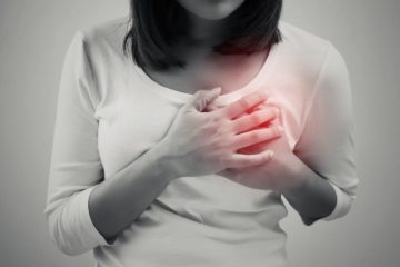 Woman is clutching her chest in acute pain caused by heart disease