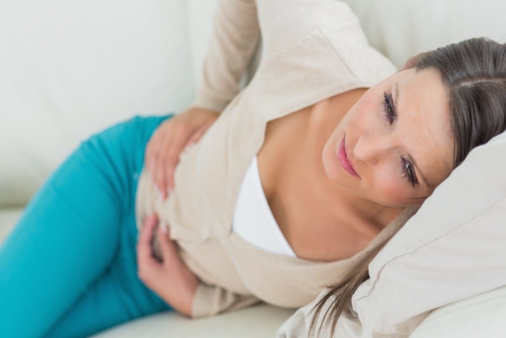 Woman lying on the bed suffering from a bad stomach bug