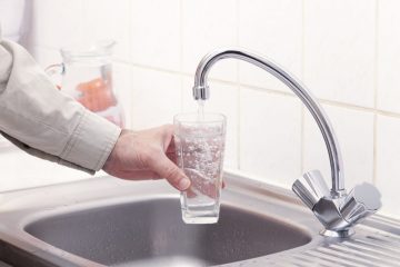 Fluorinated Water Flows into a Glass Held by a Hand